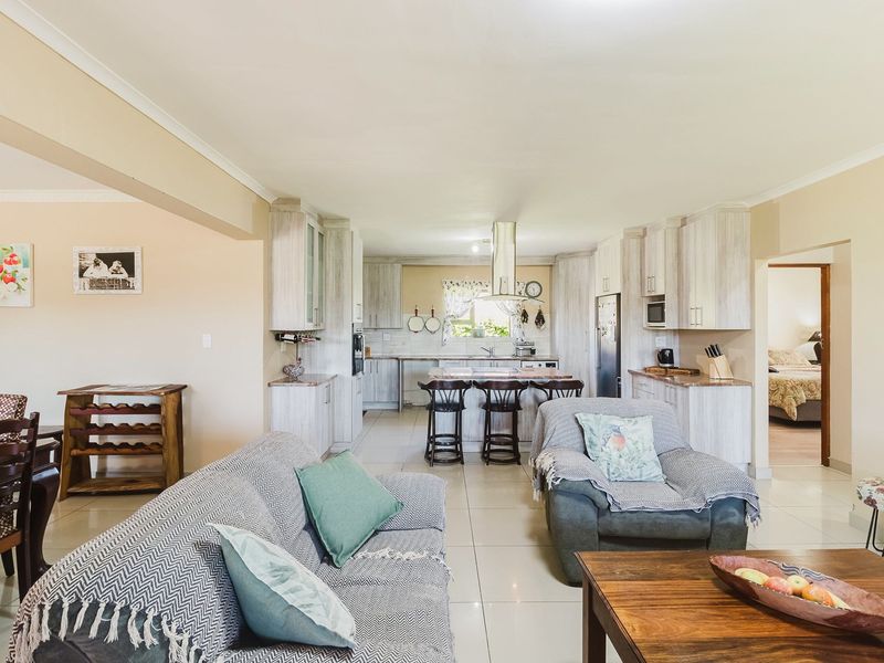 Spacious open-plan living area featuring a modern kitchen with island seating, light-toned cabinetry, and tiled flooring throughout.