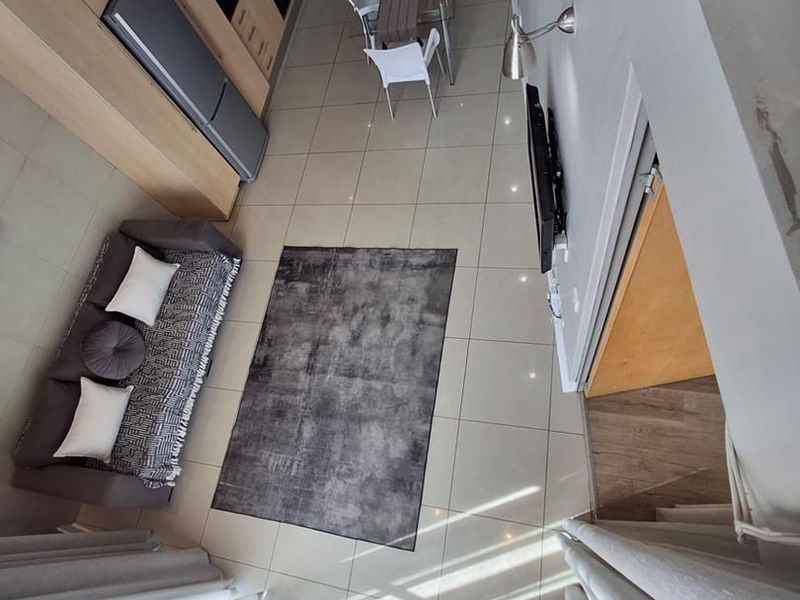 An elevated view of an open-plan living and kitchen area featuring modern cabinetry, tiled flooring, and a bright, airy layout.