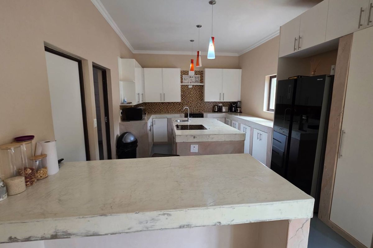 A functional kitchen featuring a central island with stone countertops, mosaic tile backsplash, and ample built-in cabinetry for storage.