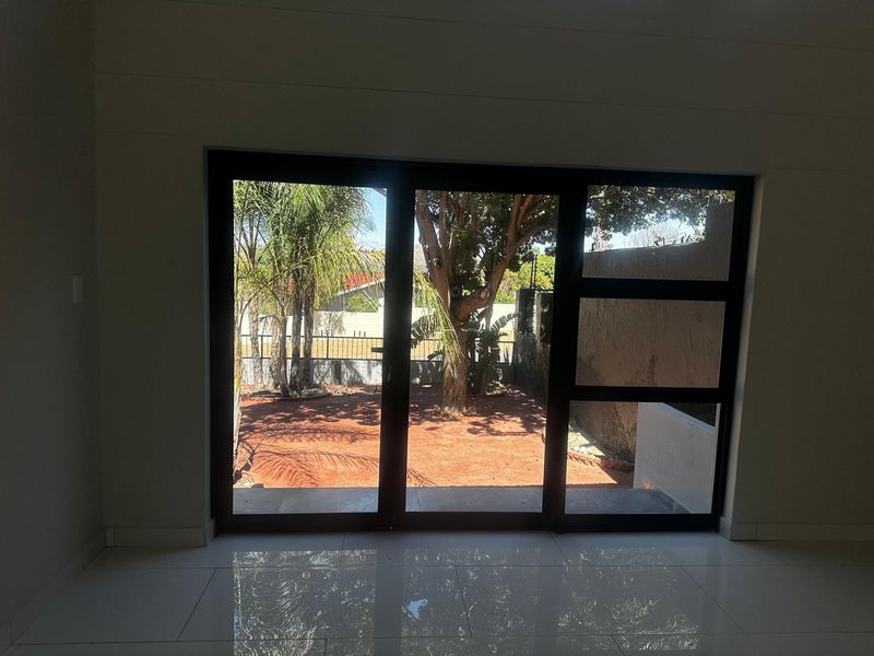 A bright, empty living area featuring large sliding glass doors that provide a clear view of the rear garden.