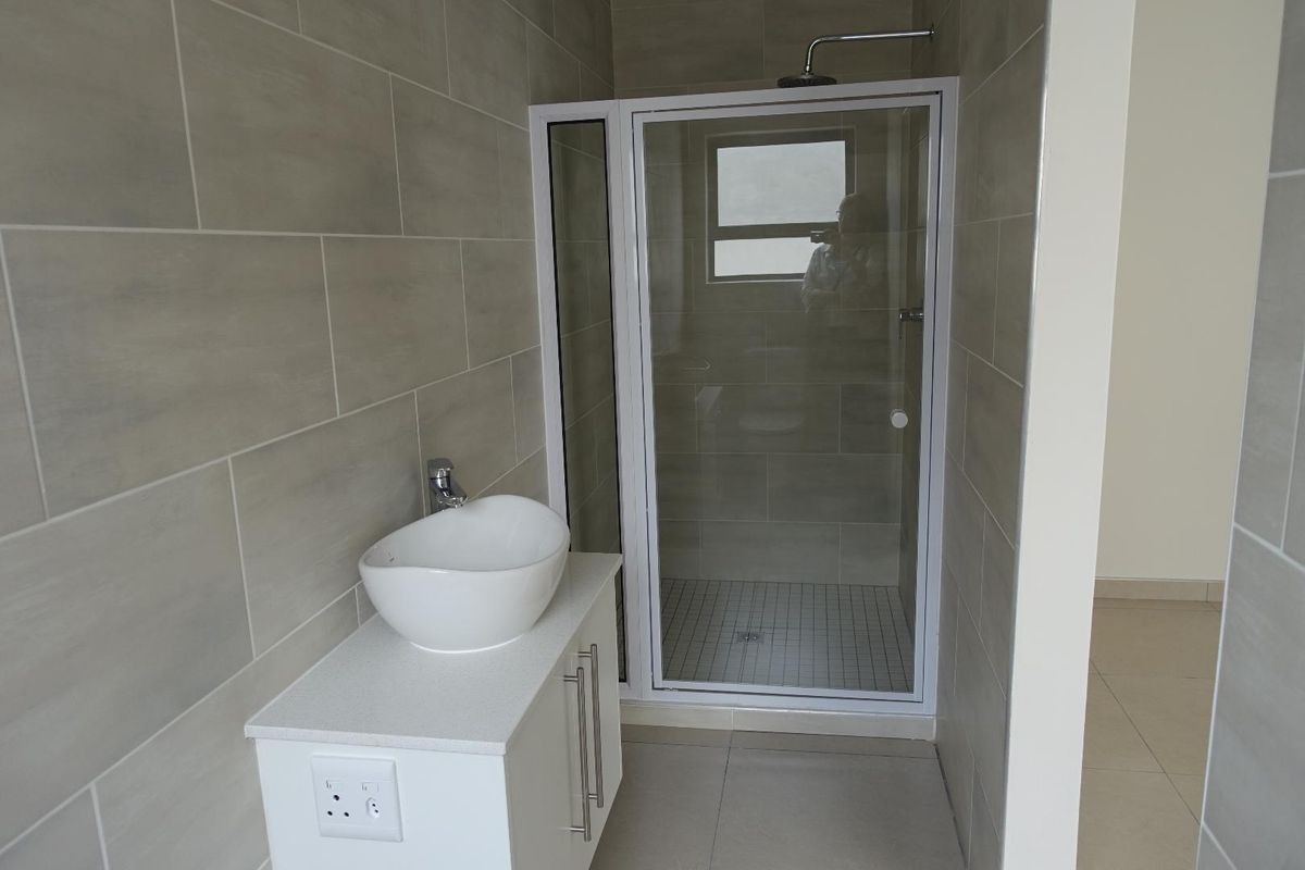 Modern bathroom featuring a glass-enclosed shower, a contemporary vessel sink vanity, and neutral wall tiling.