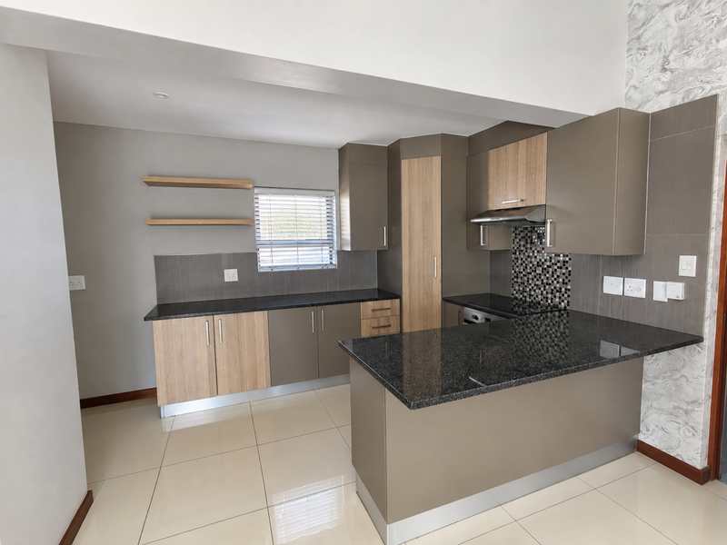 Modern kitchen featuring granite countertops, built-in cabinetry, integrated oven, extractor fan, and stylish mosaic backsplash with neutral tiled flooring.