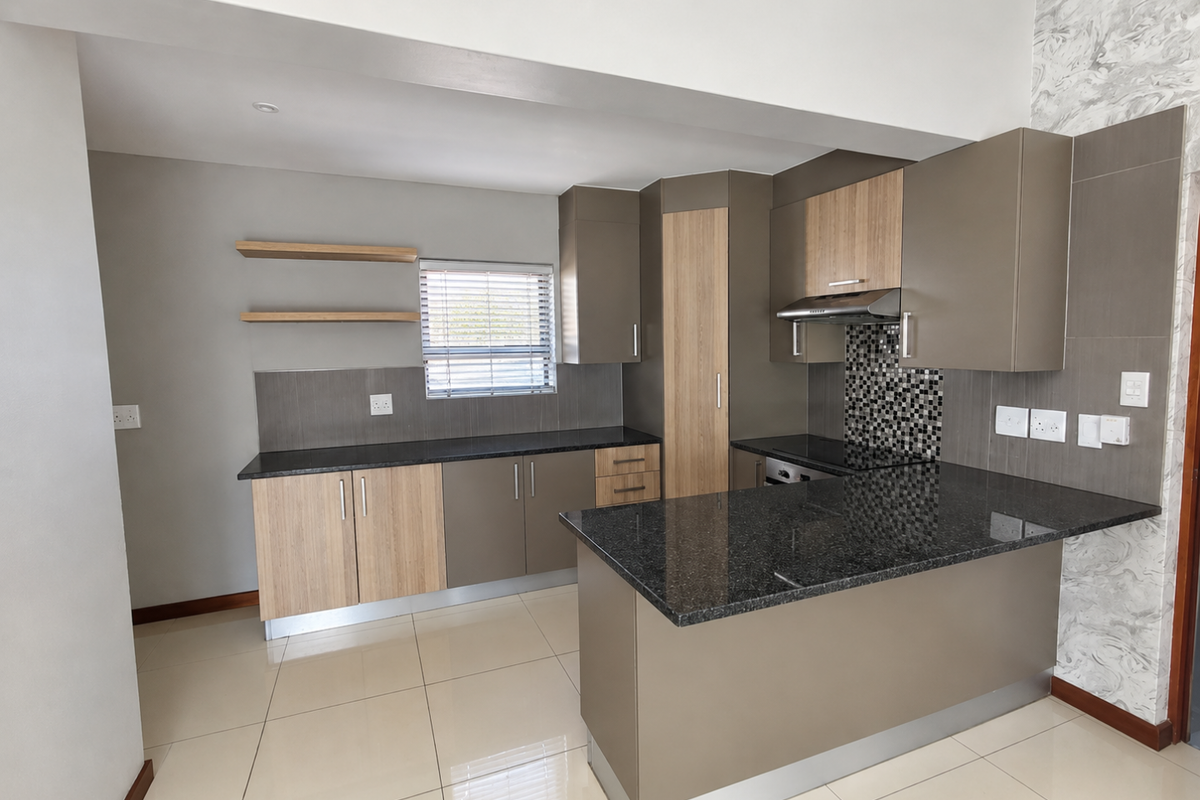 Modern kitchen featuring granite countertops, built-in cabinetry, integrated oven, extractor fan, and stylish mosaic backsplash with neutral tiled flooring.