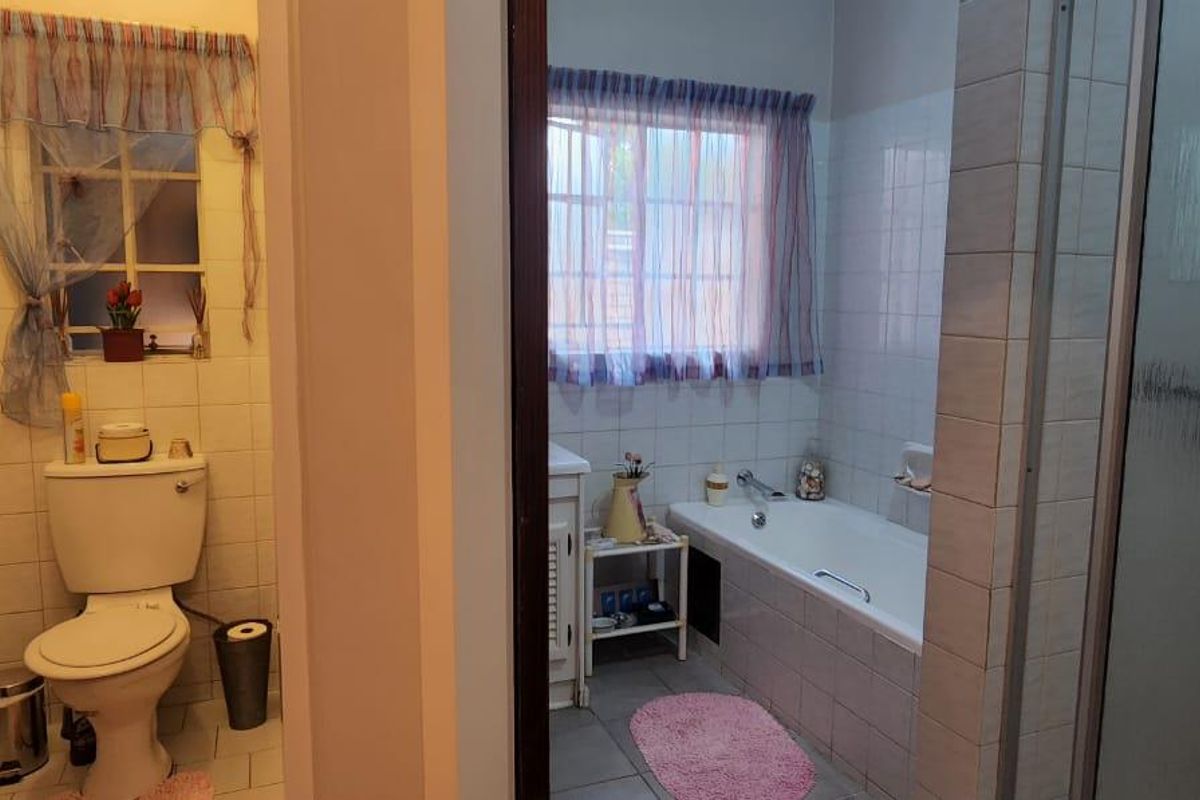 A functional bathroom featuring a separate toilet area, a built-in bathtub, and a shower enclosure with tiled walls.
