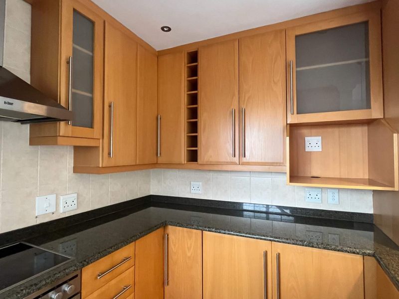 A well-maintained kitchen featuring wooden cabinetry, granite countertops, a tiled backsplash, and integrated stainless steel appliances.