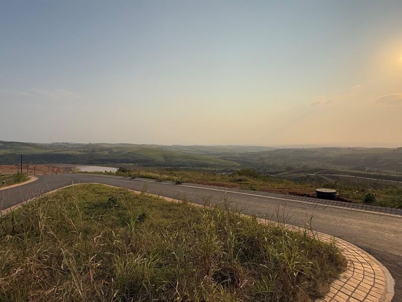 A scenic view of the surrounding landscape from a paved residential road within the estate, featuring established infrastructure and rolling hills.