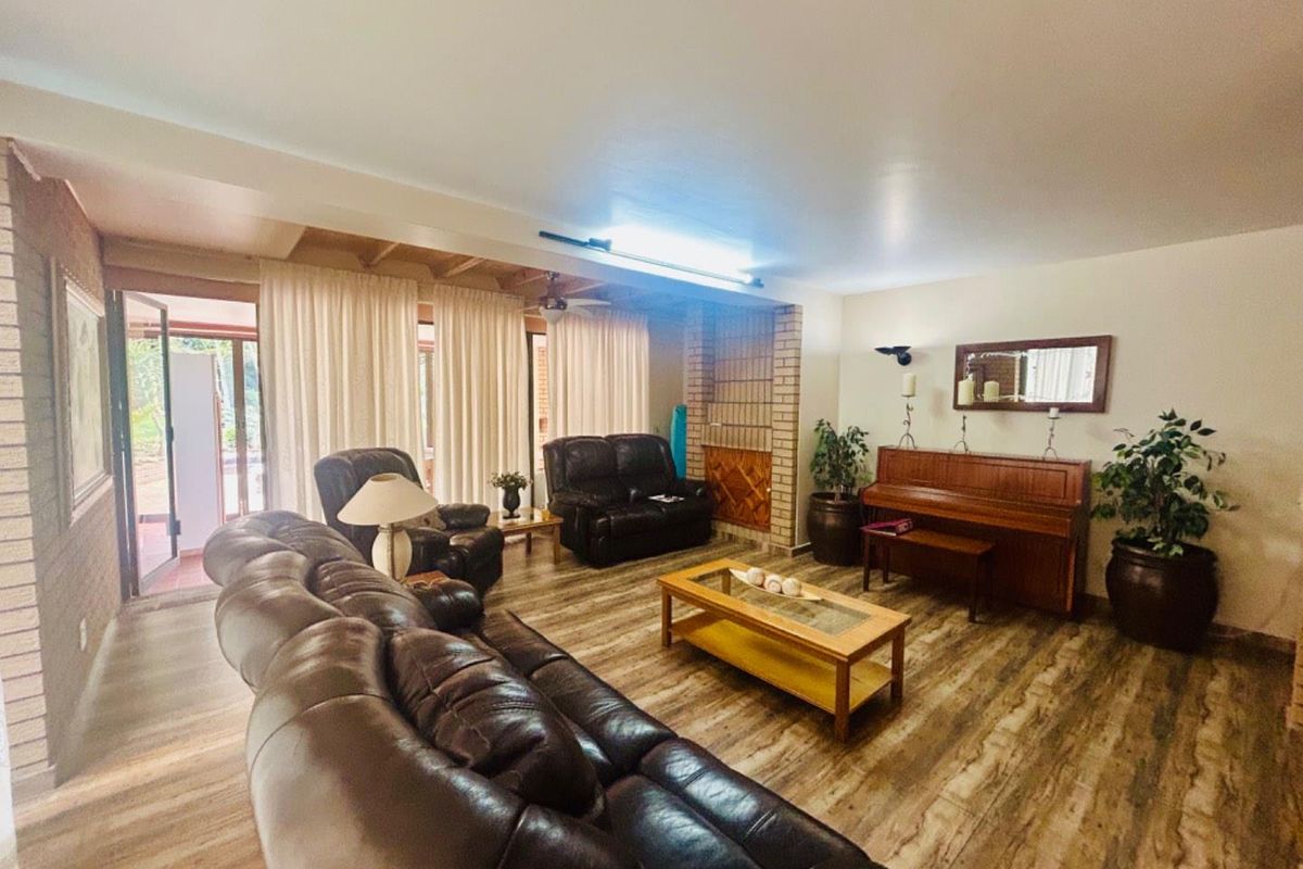 Spacious living room featuring wood-look flooring, a brick fireplace surround, and direct access to an outdoor patio area through sliding glass doors.