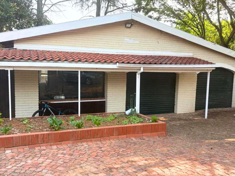 Front exterior view of a house featuring a brick driveway, double garage, and a covered walkway with a brick planter box.