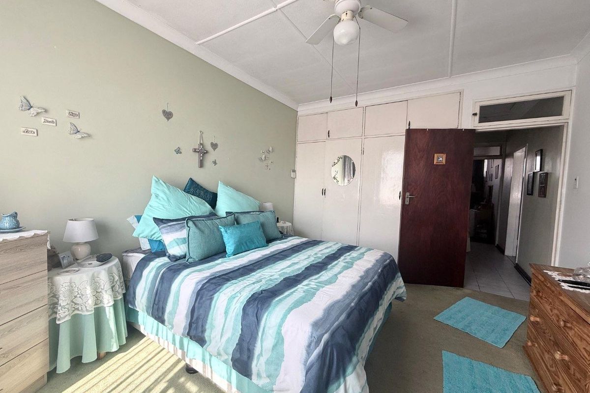 A bedroom featuring built-in storage cupboards, a ceiling fan, and carpeted flooring, offering a functional space with potential for cosmetic updates.