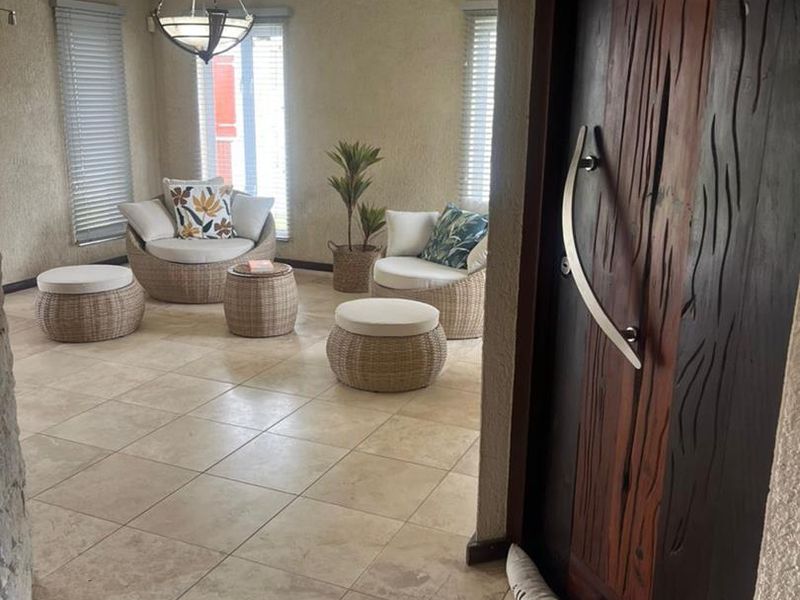 Welcoming entrance foyer featuring large ceramic floor tiles, a distinctive textured timber front door, and natural light through venetian blinds.