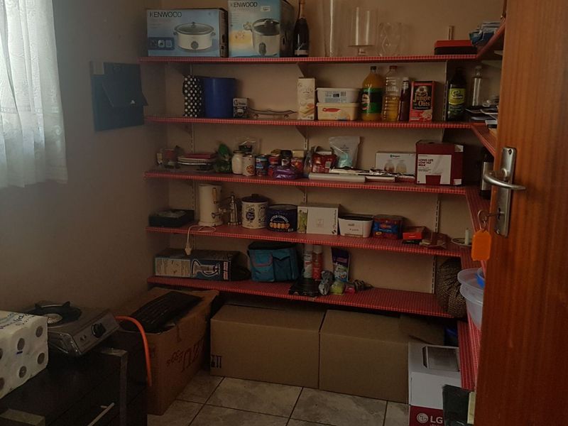 A functional scullery or pantry area featuring extensive built-in shelving and tiled flooring, providing ample storage space for kitchen essentials.