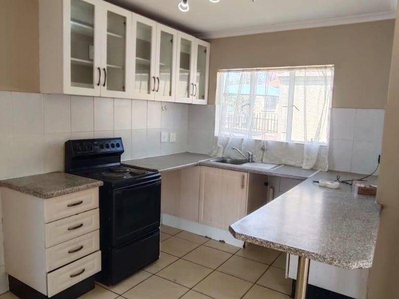 A functional kitchen featuring built-in cabinetry, laminate countertops, a freestanding stove, and tiled finishes, offering a practical layout ready for modernization.