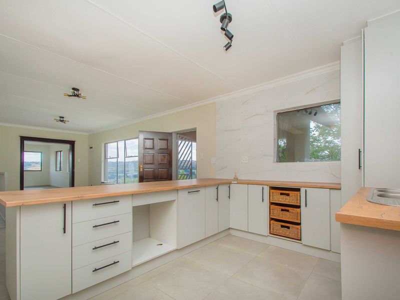 Modern kitchen featuring light-toned cabinetry, wooden countertops, marble-look splashback, and tiled flooring, offering a clean and functional workspace.