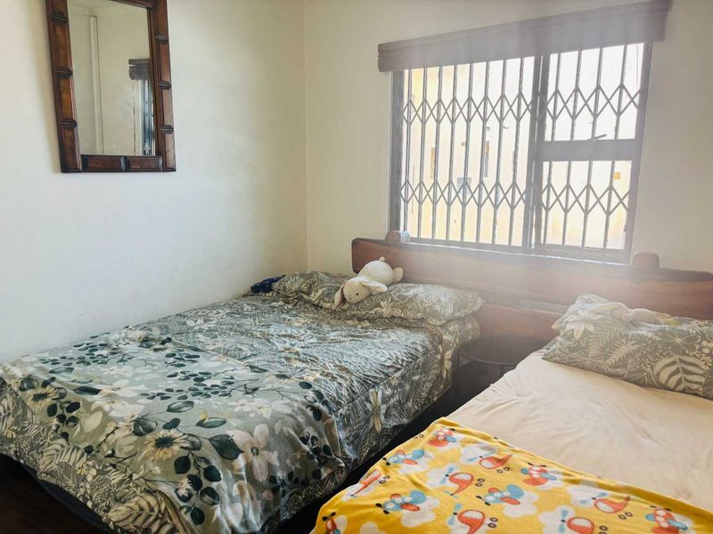 A functional bedroom featuring a window with a fitted security gate and blinds, providing natural light and essential security.