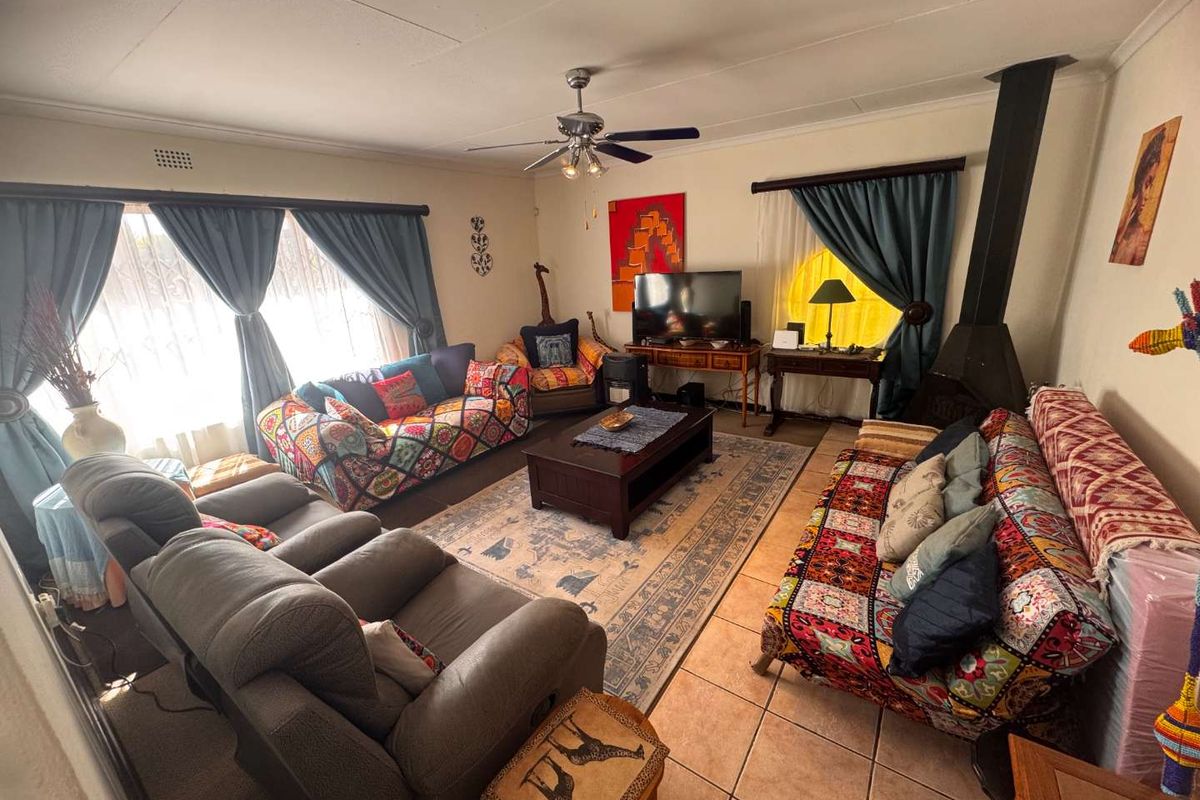 Spacious living room featuring tiled flooring, a ceiling fan, and a freestanding fireplace, offering a comfortable and functional family space.