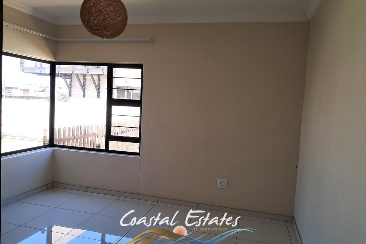 A bright, empty bedroom featuring tiled flooring, large windows, and neutral wall finishes, providing a clean and versatile space.