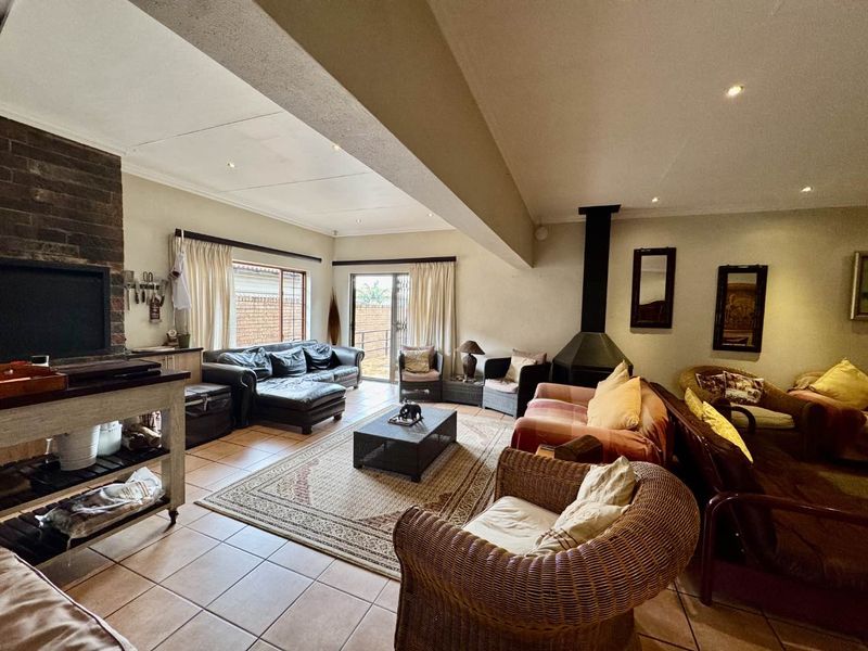Spacious living room featuring a brick fireplace, tiled flooring, and direct access to the outdoor area through sliding glass doors.