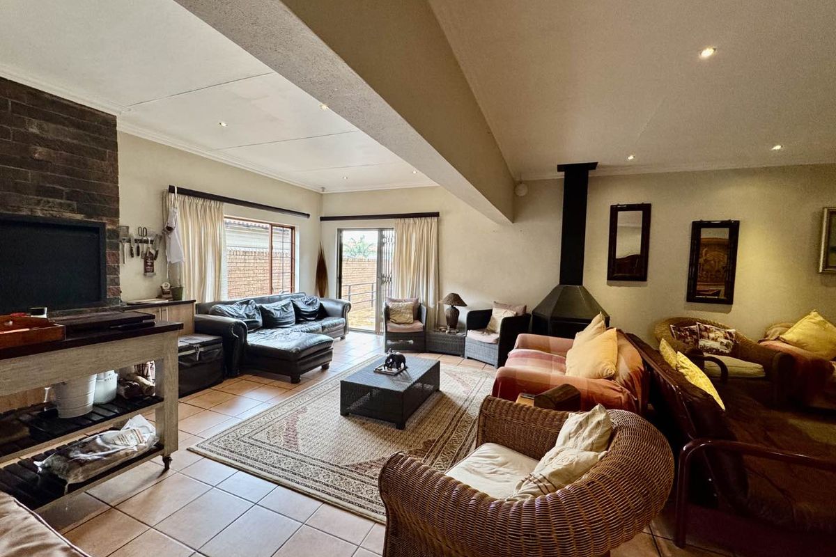 Spacious living room featuring a brick fireplace, tiled flooring, and direct access to the outdoor area through sliding glass doors.