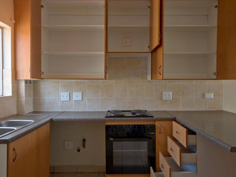 A dated kitchen featuring laminate cabinetry, a double bowl sink, and built-in oven with hob, currently requiring maintenance and cosmetic updates.
