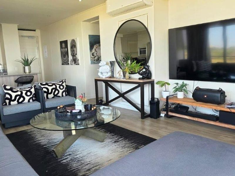 Spacious open-plan living area featuring modern laminate flooring, recessed lighting, and a split-system air conditioner, seamlessly connecting to the kitchen breakfast bar.