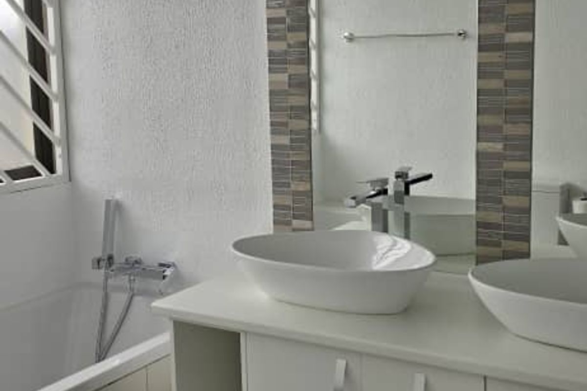 Modern bathroom featuring a double vanity with vessel sinks, a built-in bathtub, and large wall-mounted mirror with decorative tile accents.