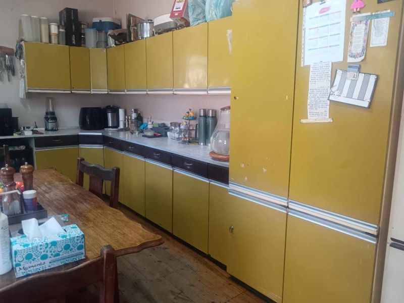 A dated kitchen featuring original laminate cabinetry and countertops with timber flooring, offering significant potential for a modern renovation.