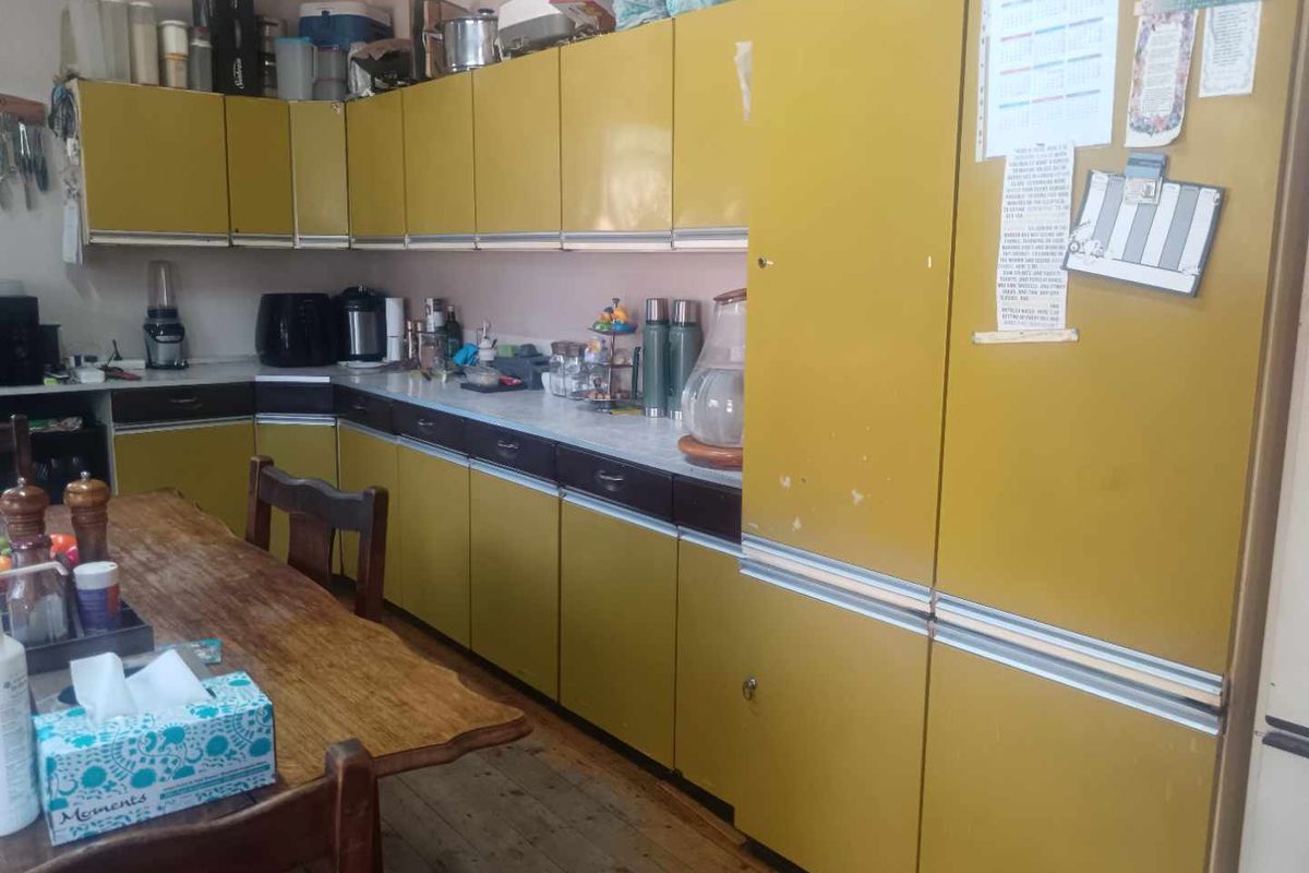 A dated kitchen featuring original laminate cabinetry and countertops with timber flooring, offering significant potential for a modern renovation.