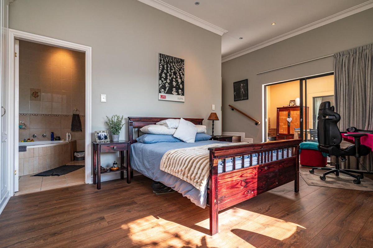 Spacious bedroom featuring laminate flooring, recessed lighting, and an integrated en-suite bathroom with a bathtub, plus direct access to an outdoor area.