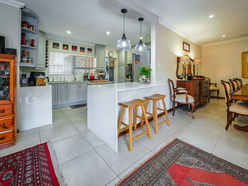 Open-plan kitchen and dining area featuring a central island with quartz countertops, modern pendant lighting, and neutral tiled flooring throughout.