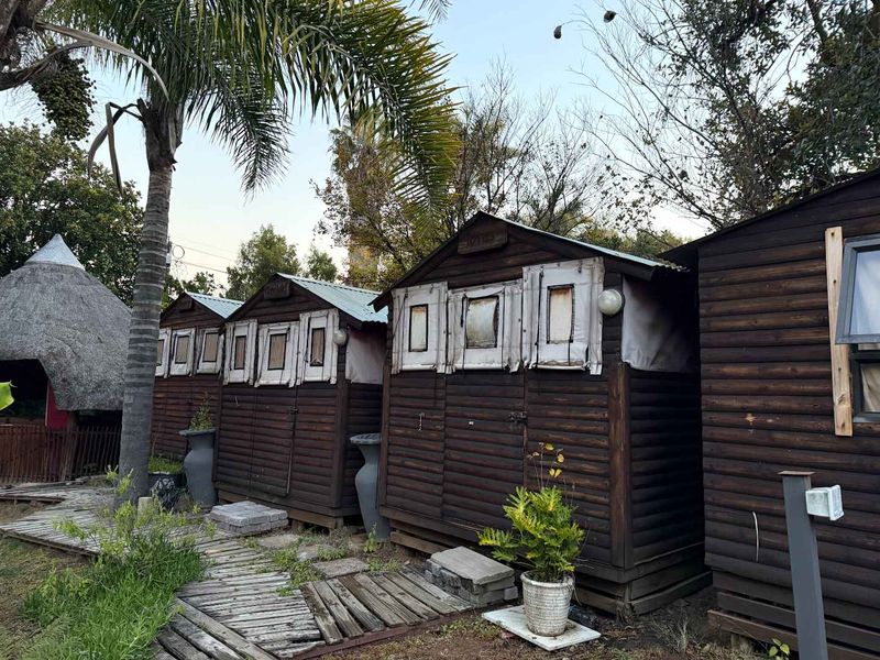 Exterior view of multiple timber-clad cottage units featuring corrugated metal roofing and a wooden walkway path.