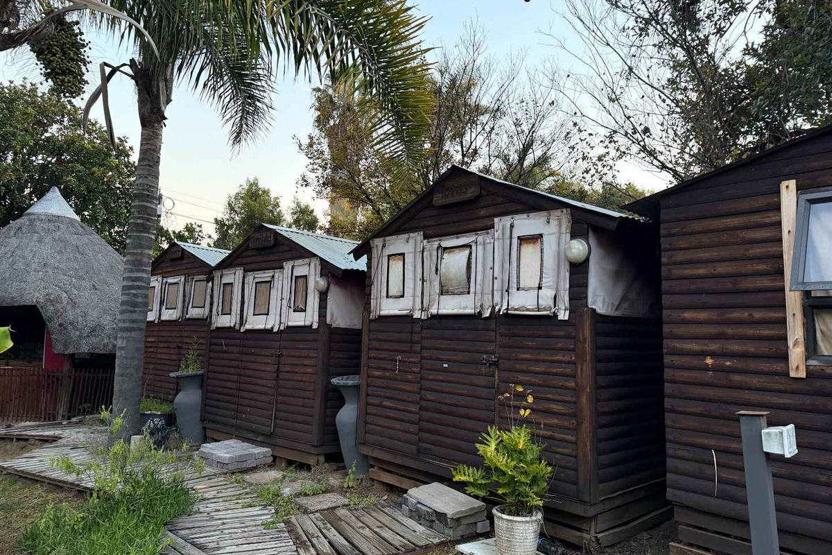 Exterior view of multiple timber-clad cottage units featuring corrugated metal roofing and a wooden walkway path.