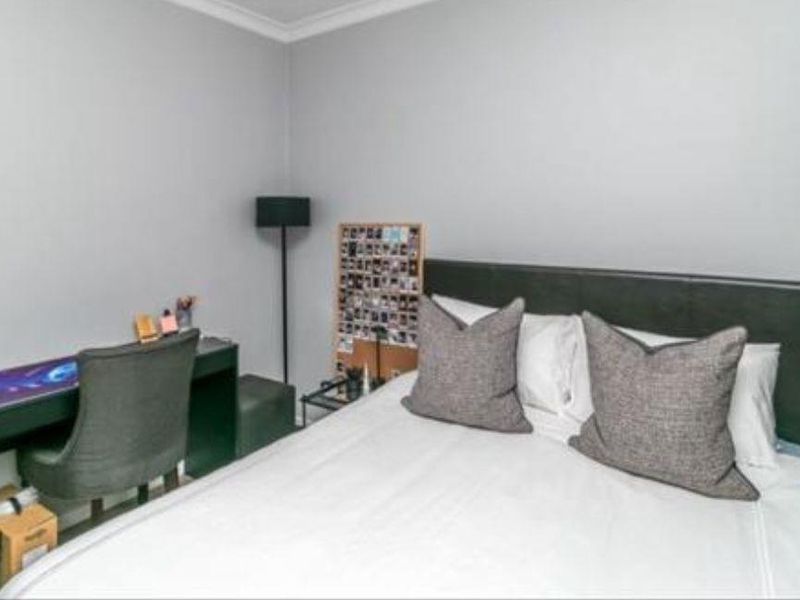 A functional bedroom featuring neutral wall finishes and coving, providing a comfortable space for rest and study.