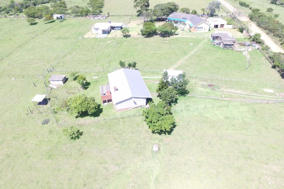 Aerial view of a farm property featuring a main dwelling, multiple outbuildings, fenced paddocks, and surrounding rural landscape.