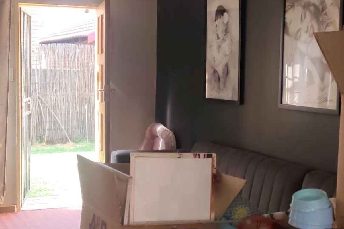 A living room area featuring a dark accent wall and direct access to an outdoor space through a security gate.