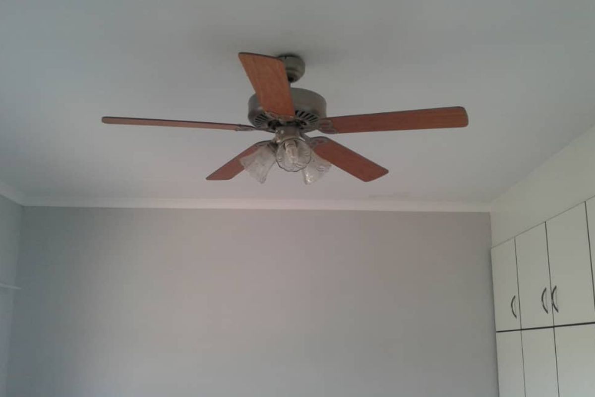 A bedroom interior featuring a ceiling fan with integrated lighting and built-in white cabinetry.