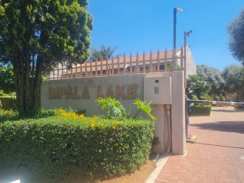 The entrance to Impala Lake complex featuring a secure boundary wall, security spikes, and a boom gate access point.