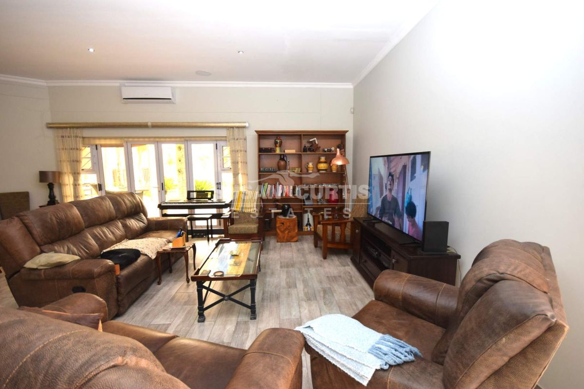 Spacious living room featuring wood-look tile flooring, recessed ceiling lighting, and sliding glass doors providing access to the outdoor area.