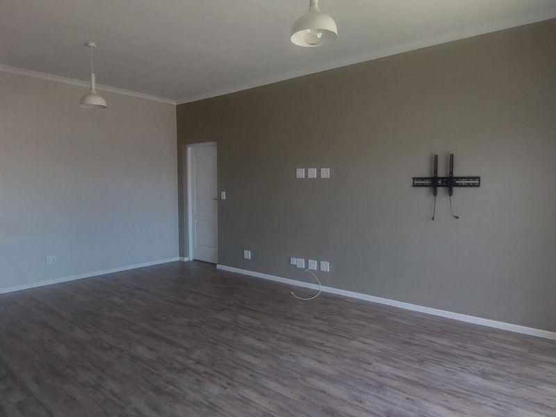 Spacious open-plan living area featuring modern laminate flooring, neutral wall tones, and integrated electrical points, providing a versatile blank canvas for interior design.