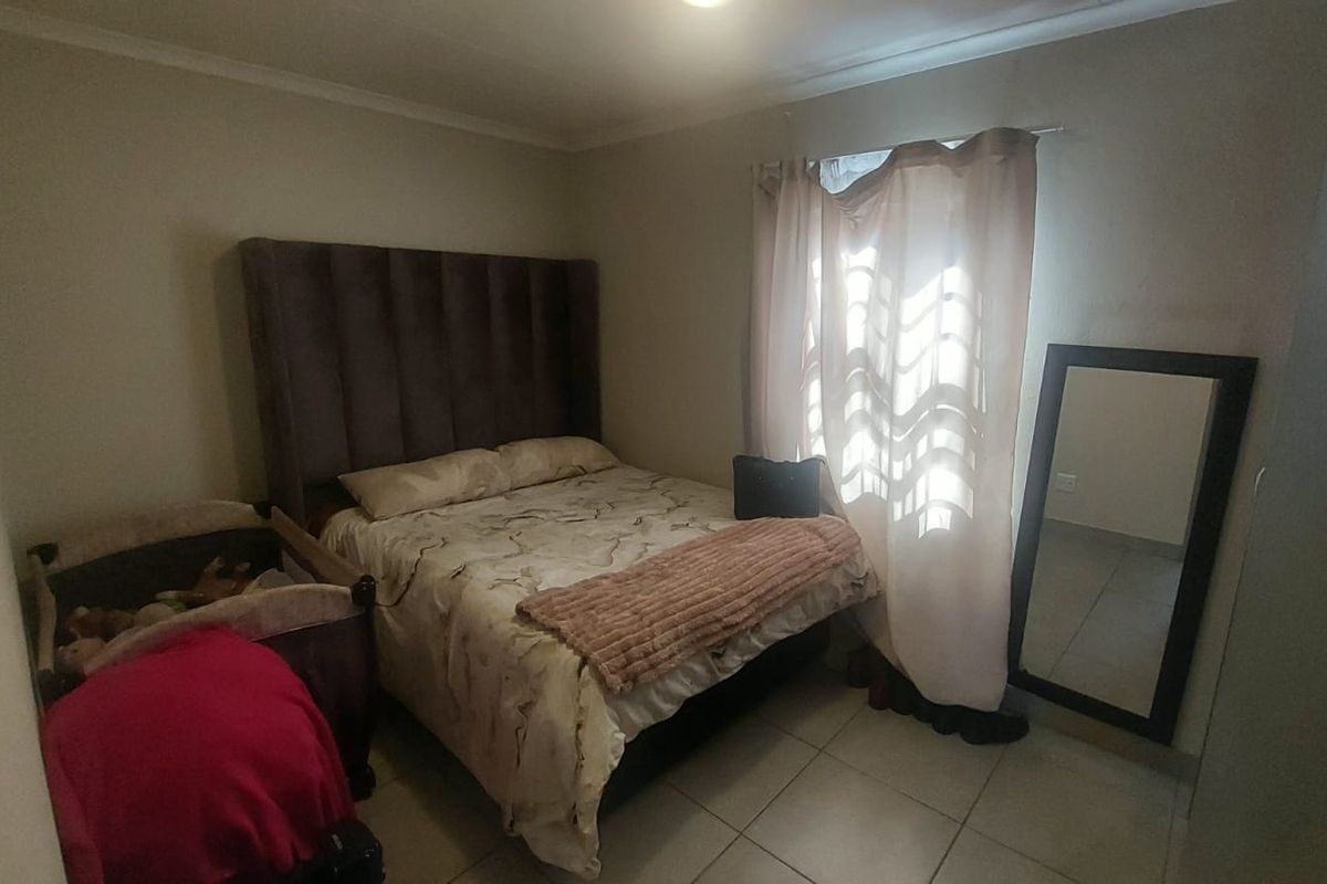 A functional bedroom featuring tiled flooring and a window with curtain treatments.