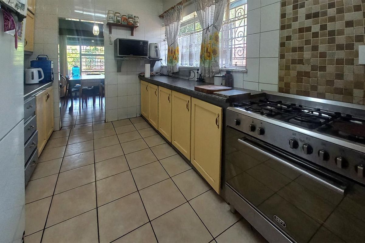 A functional kitchen featuring tiled flooring, built-in cabinetry, a gas stove with oven, and a mosaic tile backsplash.