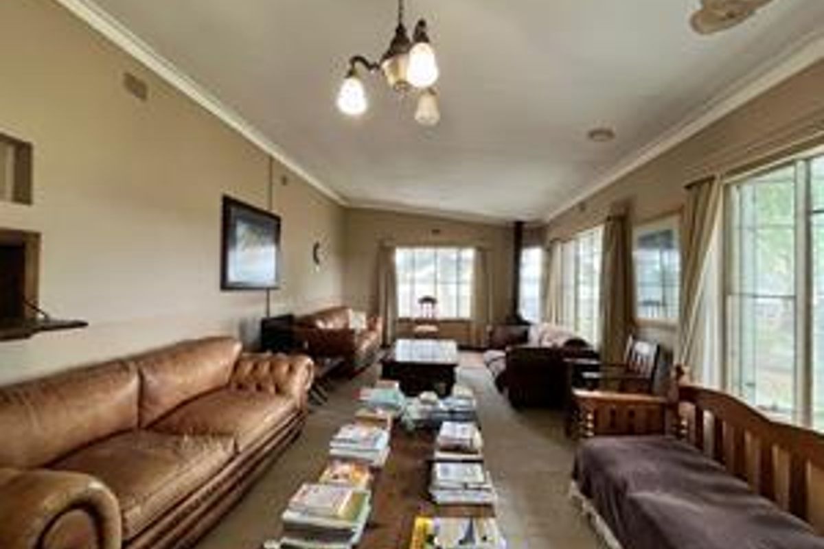 Spacious living room featuring large windows, a built-in fireplace, and classic crown molding, offering a comfortable and traditional atmosphere.