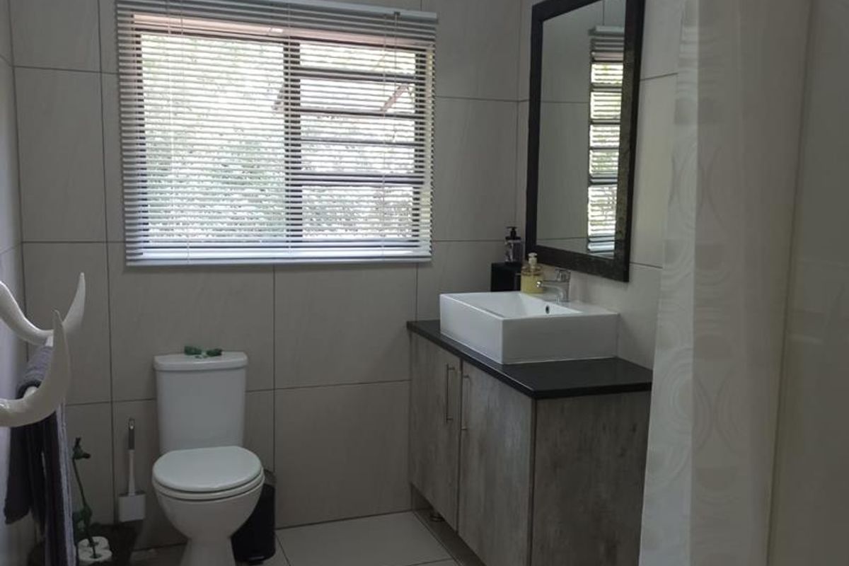 A modern bathroom featuring large-format wall tiles, a floating vanity with a vessel sink, a toilet, and a shower area with a curtain.