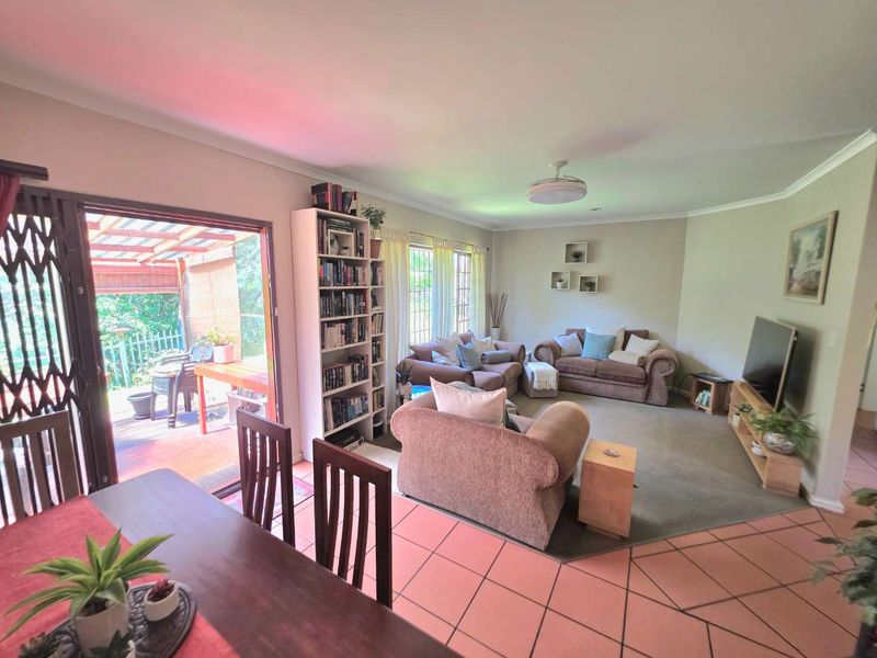 Open plan living and dining area featuring a mix of tiled and carpeted flooring with direct access to an outdoor patio through sliding doors.