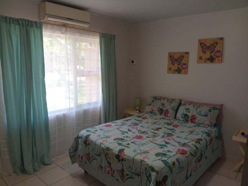 A functional bedroom featuring tiled flooring and a wall-mounted split-system air conditioning unit.