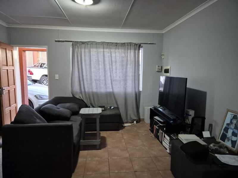 A functional living room featuring tiled flooring and standard ceiling finishes, providing a comfortable space for relaxation.