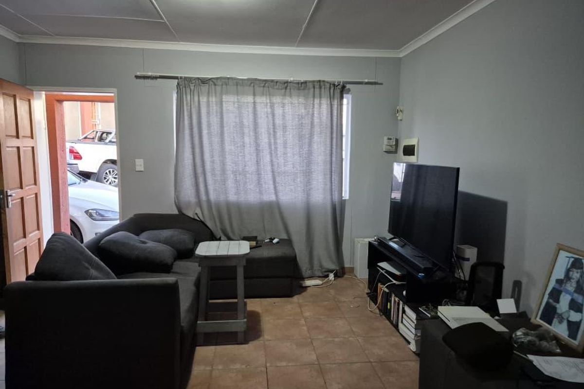 A functional living room featuring tiled flooring and standard ceiling finishes, providing a comfortable space for relaxation.