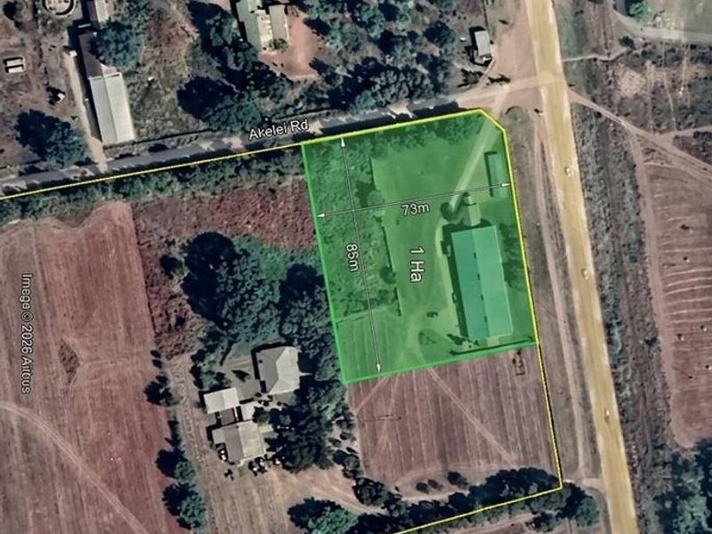 Aerial view of a one-hectare commercial vacant land plot featuring a large building structure and direct road access.