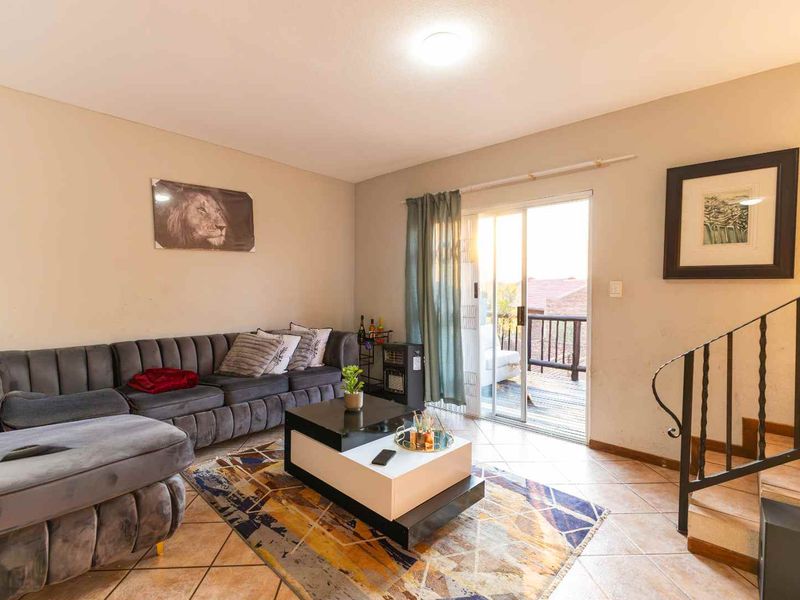 A living room featuring tiled flooring, a wrought iron staircase railing, and a sliding glass door providing access to an outdoor area.
