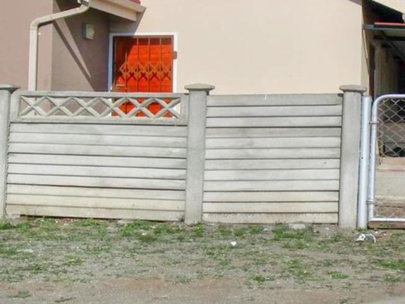 Front exterior view of a townhouse featuring a precast concrete boundary wall, security gate, and a satellite dish mounted on the facade.