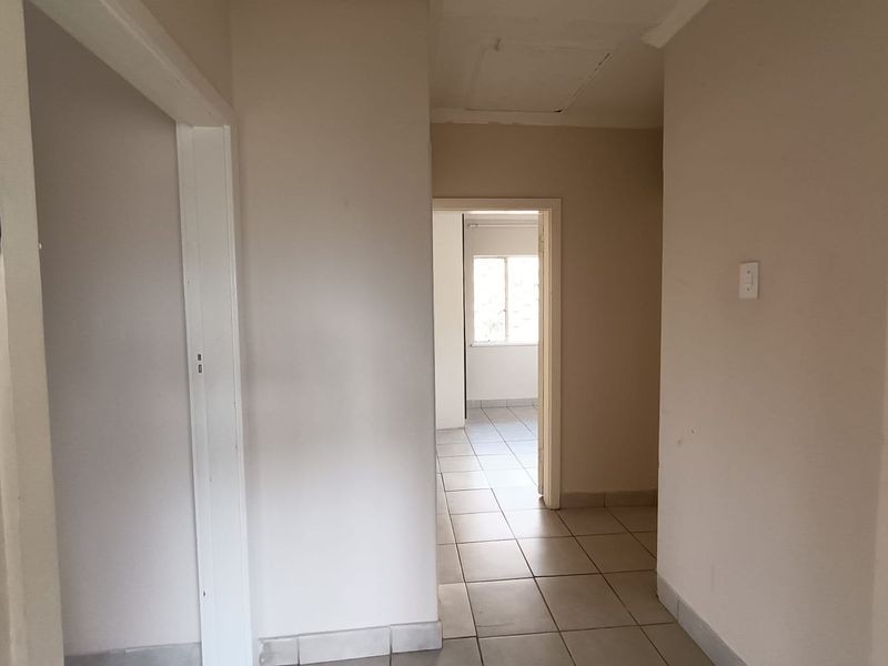 A neutral, tiled hallway providing access to adjacent rooms, featuring clean lines and a functional layout.